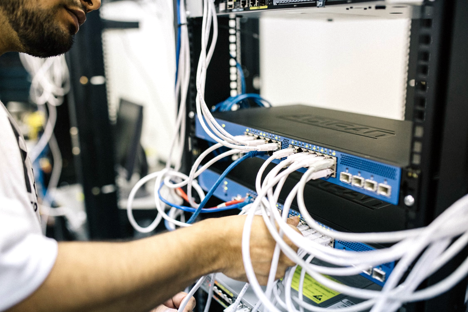 Network engineer installing internet equipment and connecting switches in a rack